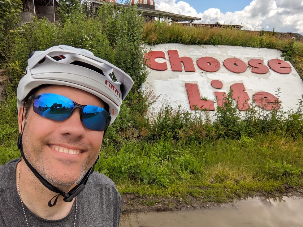 me in sunglasses smiling next to a sign that says choose life